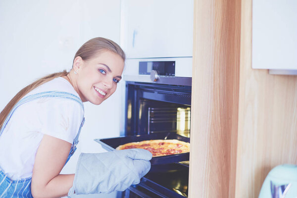 Happy young woman cooking pizza at home