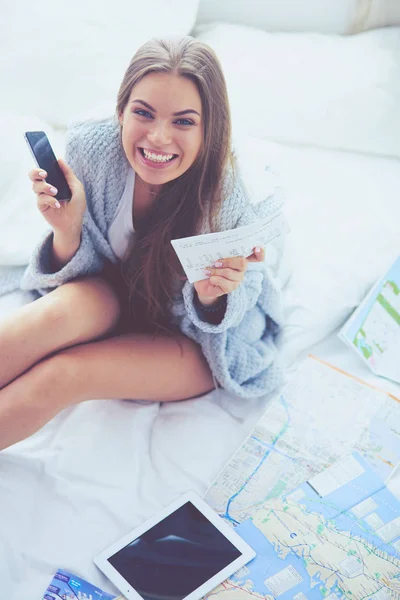 Mujer joven y relajada sentada en la cama con una taza de café y una tableta digital —  Fotos de Stock