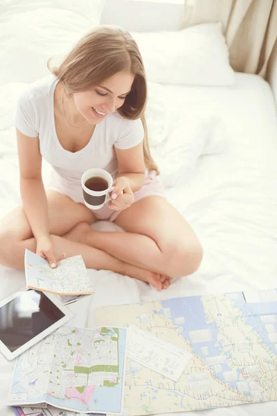 Entspannte junge Frau sitzt mit einer Tasse Kaffee und digitalem Tablet im Bett — Stockfoto