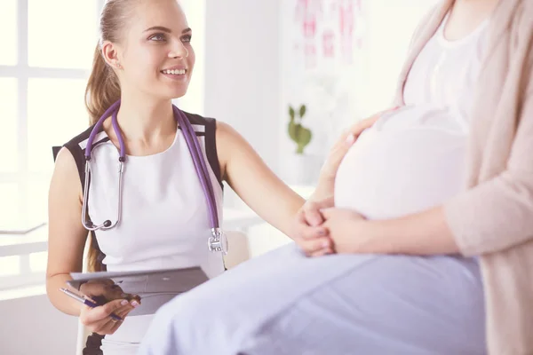 Fiatal nő orvos sztetoszkóppal és tablettával beszél terhes nővel a kórházban. — Stock Fotó