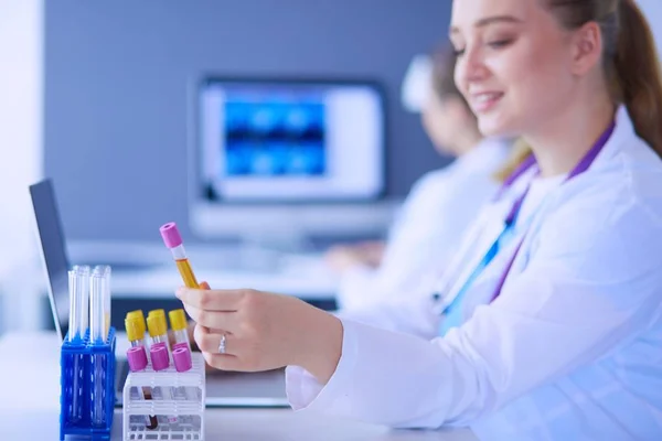 Asistente de laboratorio poniendo tubos de ensayo en el soporte, Vista de primer plano se centró en los tubos con pruebas . —  Fotos de Stock