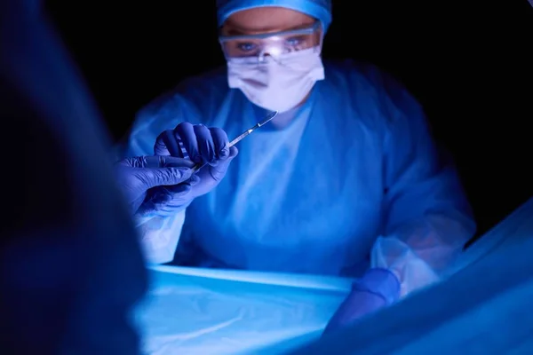 어두운 배경에서 수술을 하는 의사. — 스톡 사진