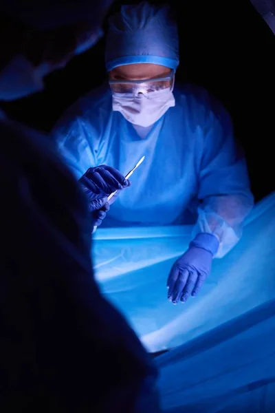 Doktor karanlık bir arka planda ameliyat yapıyor.. — Stok fotoğraf