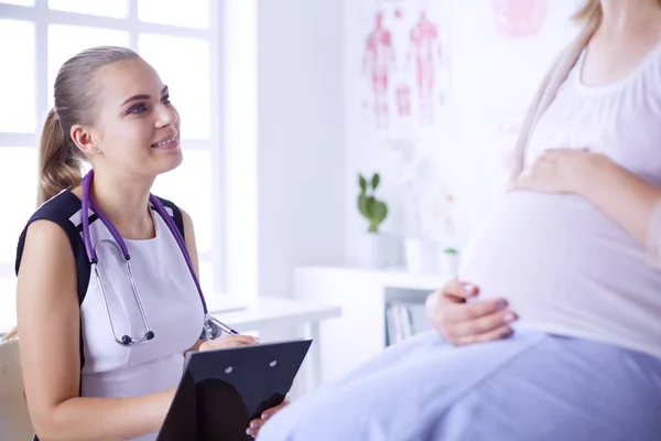 带听诊器和石碑的年轻女医生在医院与孕妇交谈. — 图库照片