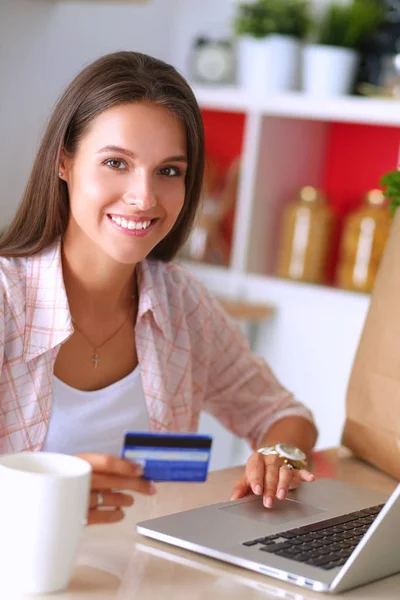 面带笑容的女人，网上购物在厨房中使用平板电脑和信用卡 — 图库照片
