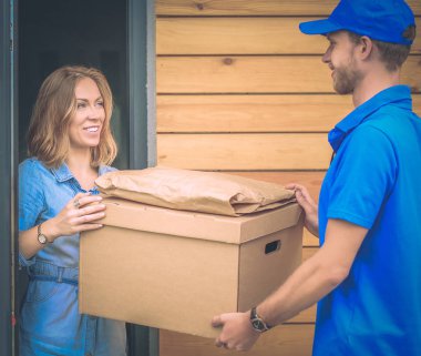 Mavi üniformalı gülümseyen kurye servis konseptine paket kutusu teslim eden teslimatçı. Mavi üniformalı gülümseyen teslimatçı.
