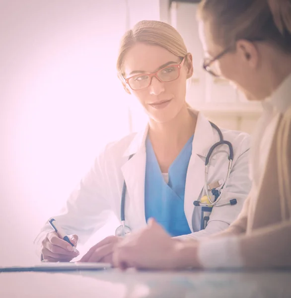 Arzt und Patient diskutieren etwas, am Schreibtisch sitzend. — Stockfoto