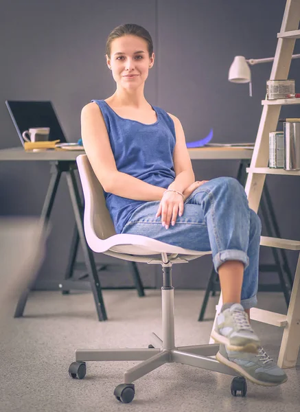 Giovane donna seduta sulla scrivania in ufficio — Foto Stock