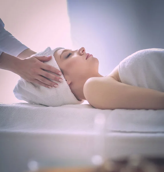 Mujer joven acostada en una mesa de masaje, relajándose con los ojos cerrados. Una mujer. Salón de spa —  Fotos de Stock