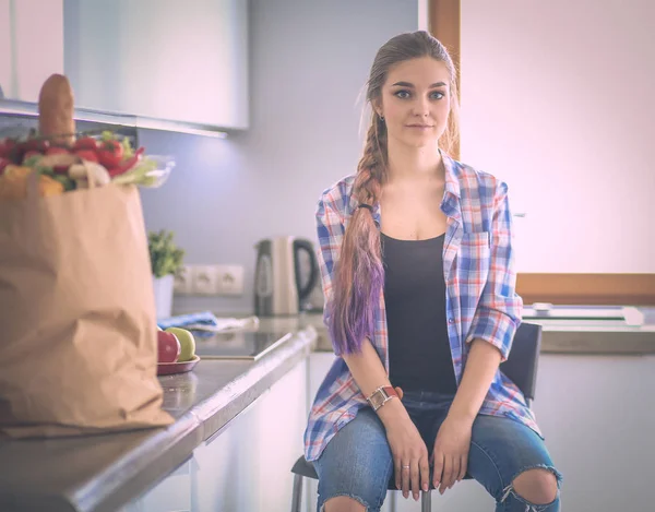 Portrait of young woman standing with arms crossed against kitchen background. — Stock Photo, Image