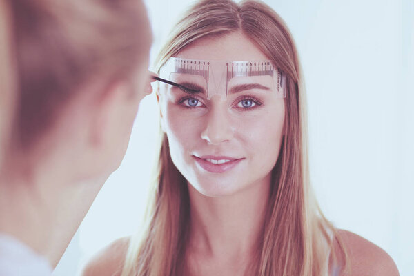 Permanent makeup for eyebrows. Closeup of beautiful woman with thick brows in beauty salon.