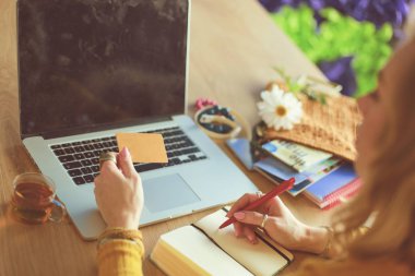 Genç bir kadın kahve molasında ya da kahve molasında dizüstü bilgisayar kullanıyor..