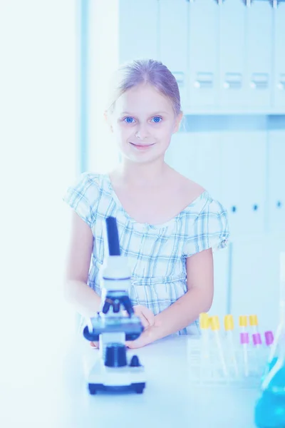 Schoolmeisje op zoek via Microscoop in de wetenschap klasse. — Stockfoto
