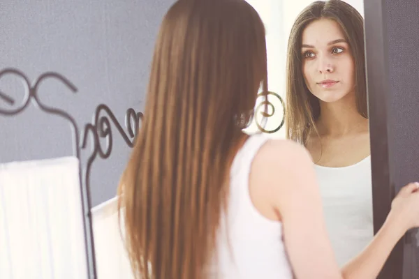 Junge Frau spiegelt sich zu Hause im Spiegel. — Stockfoto