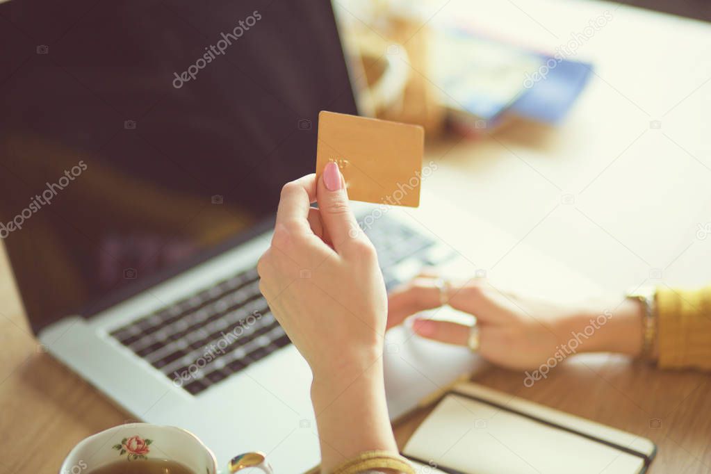 Young woman holding credit card and using laptop computer. Online shopping concept.