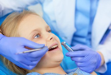 Küçük kız dişçi ofisinde oturuyor..