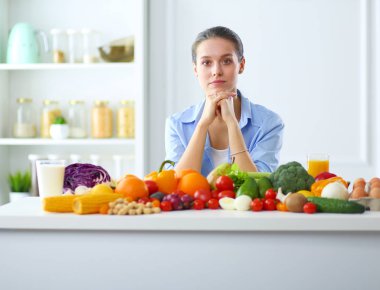 Ahşap iç kısımda meyve ve sebze dolu masada oturan genç ve tatlı bir kadın..