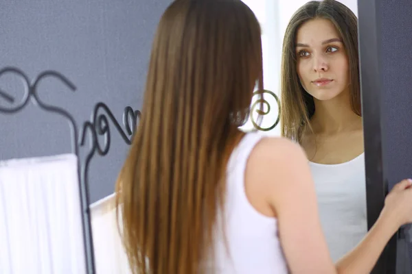 Jovem mulher olhando-se reflexão no espelho em casa . — Fotografia de Stock