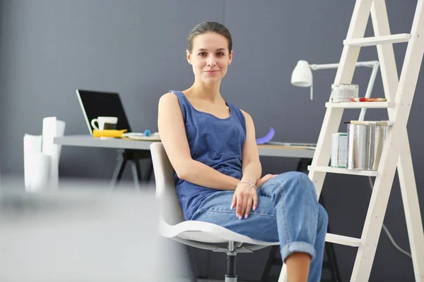 Mujer joven sentada en el escritorio con instrumentos, plano y portátil. — Foto de Stock