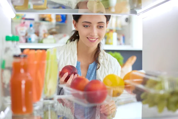 Portrait of female standing near open fridge full of healthy food, vegetables and fruits. Portrait of female — Stock Photo, Image