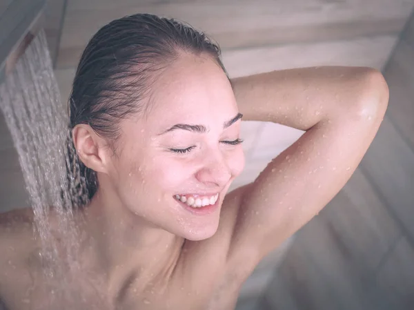 Jeune femme belle sous la douche dans la salle de bain — Photo