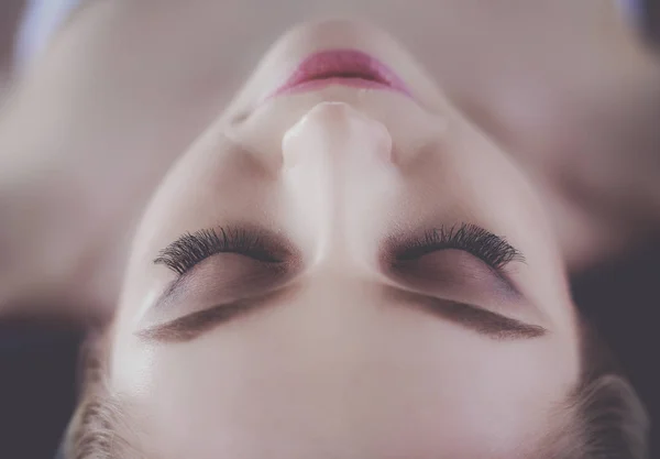 Mujer joven acostada en una mesa de masaje, relajándose con los ojos cerrados. Una mujer. Salón de spa —  Fotos de Stock