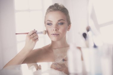 Genç bir kadının banyoya yüz pudrası sürerken fotoğrafı.