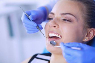 Dişçi muayenehanesinde diş muayenesi yapan ağzı açık genç bir kadın hasta..