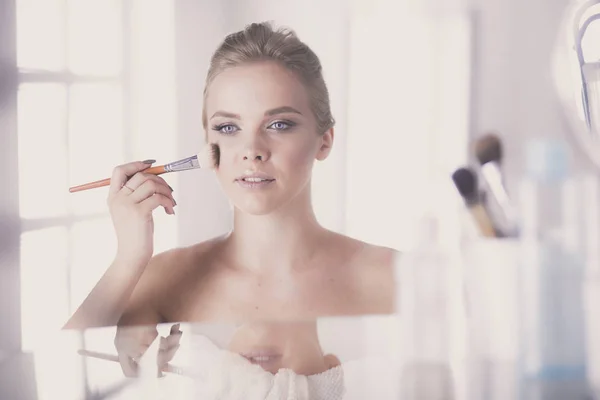 Une photo d'une jeune femme appliquant de la poudre visage dans la salle de bain — Photo