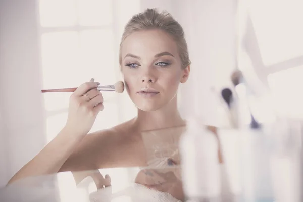 En bild av en ung kvinna som applicerar ansiktspulver i badrummet — Stockfoto