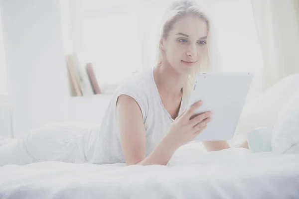 Chica sosteniendo tableta digital con pantalla en blanco y sonriendo a la cámara en el dormitorio — Foto de Stock