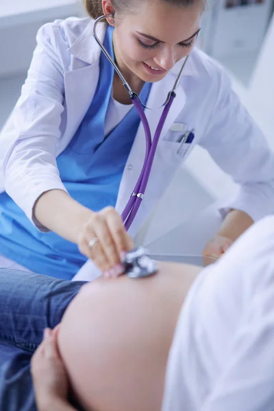 Doctora joven examinando a una mujer embarazada en la clínica. — Foto de Stock