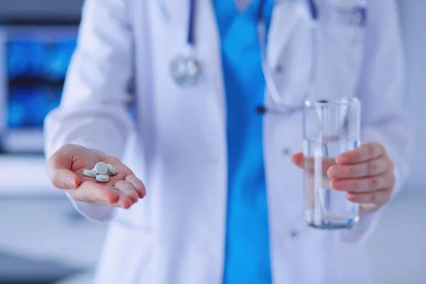 Colpo di mani di dottori che tengono pillole e vetro d'acqua a clinica. — Foto Stock