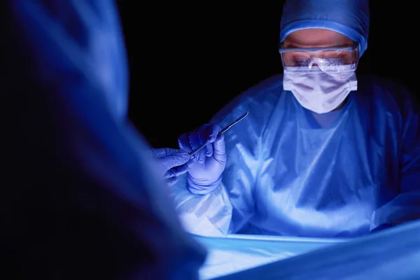 Oříznutý obrázek skalpelu s lékaři provádějícími operaci. — Stock fotografie