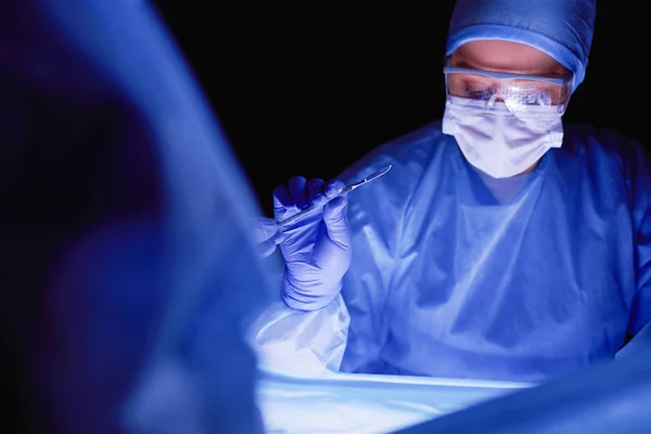 Imagen recortada del bisturí tomada médicos que realizan la cirugía. — Foto de Stock