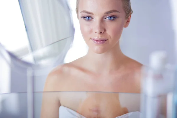 Giovane donna in accappatoio guardando nello specchio del bagno — Foto Stock