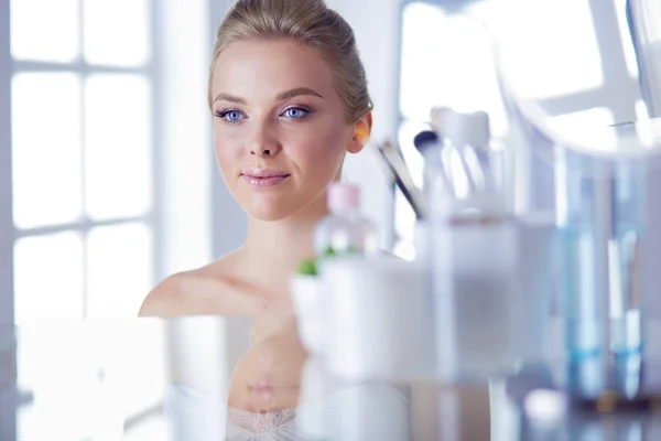 Giovane donna in accappatoio guardando nello specchio del bagno — Foto Stock