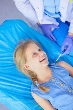 Küçük kız dişçi ofisinde oturuyor..