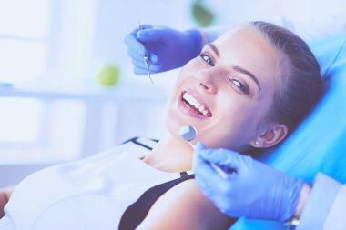 Dişçi muayenehanesinde diş muayenesi yapan ağzı açık genç bir kadın hasta..