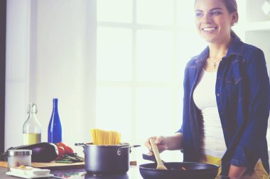 Mutfakta yemek hazırlayan genç bir kadın.