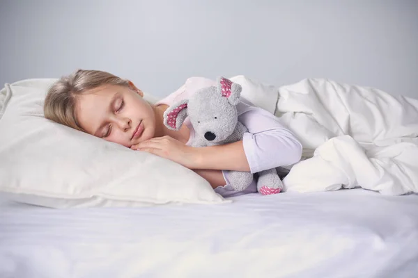 Enfant petite fille dort dans le lit avec un nounours jouet . — Photo