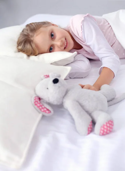Kleines Mädchen schläft im Bett mit einem Spielzeug-Teddybär. — Stockfoto