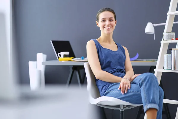 Jonge vrouw zit aan het bureau met instrumenten, plan en laptop. — Stockfoto