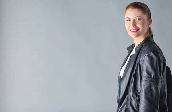 Portrait of beautiful young brunette woman in stylish black jacket on gray. — Stock Photo, Image