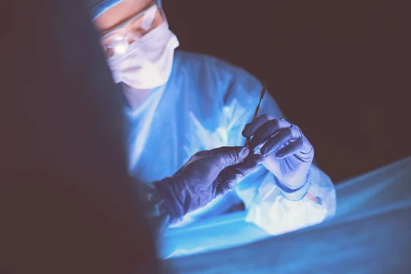 Doktor karanlık bir arka planda ameliyat yapıyor.. — Stok fotoğraf