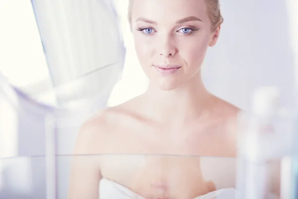 Young woman in bathrobe looking in bathroom mirror — Stock Photo, Image