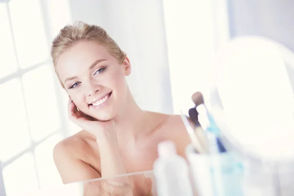 Mujer joven en albornoz mirando en el espejo del baño — Foto de Stock