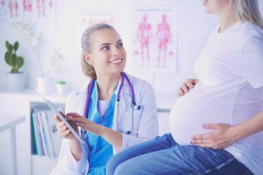 Gülümseyen kadın doktor resimlerini tablette hastanedeki hamile genç bayana gösteriyor..