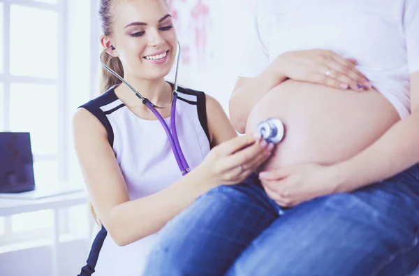 Mladá žena lékař vyšetřuje těhotnou ženu na klinice. — Stock fotografie