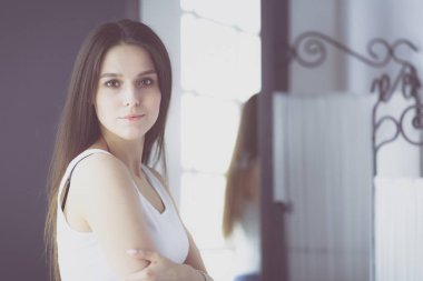 Genç kadın kendini evde aynada yansıma arıyor.